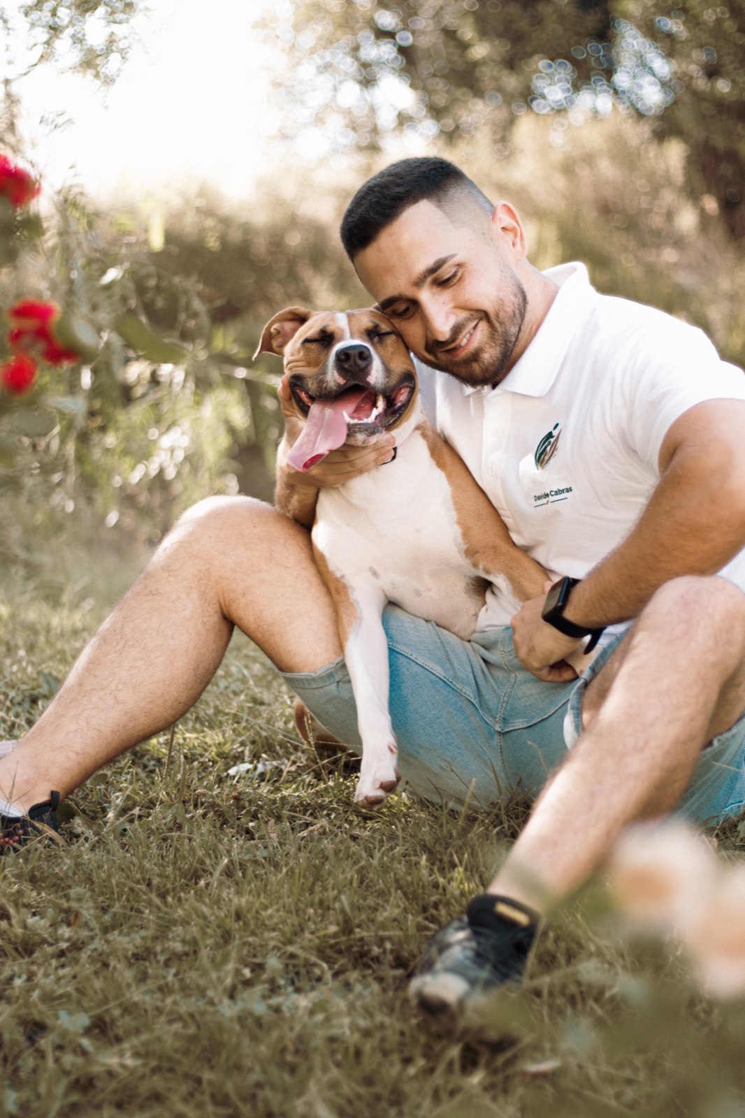 Davide Cabras gioca all'aperto con un cane, tenendolo tra le braccia